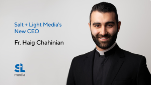 Fr. Haig Chahinian, the new CEO of Salt + Light Media, is pictured in a photo. He is standing in front of the SL media logo.